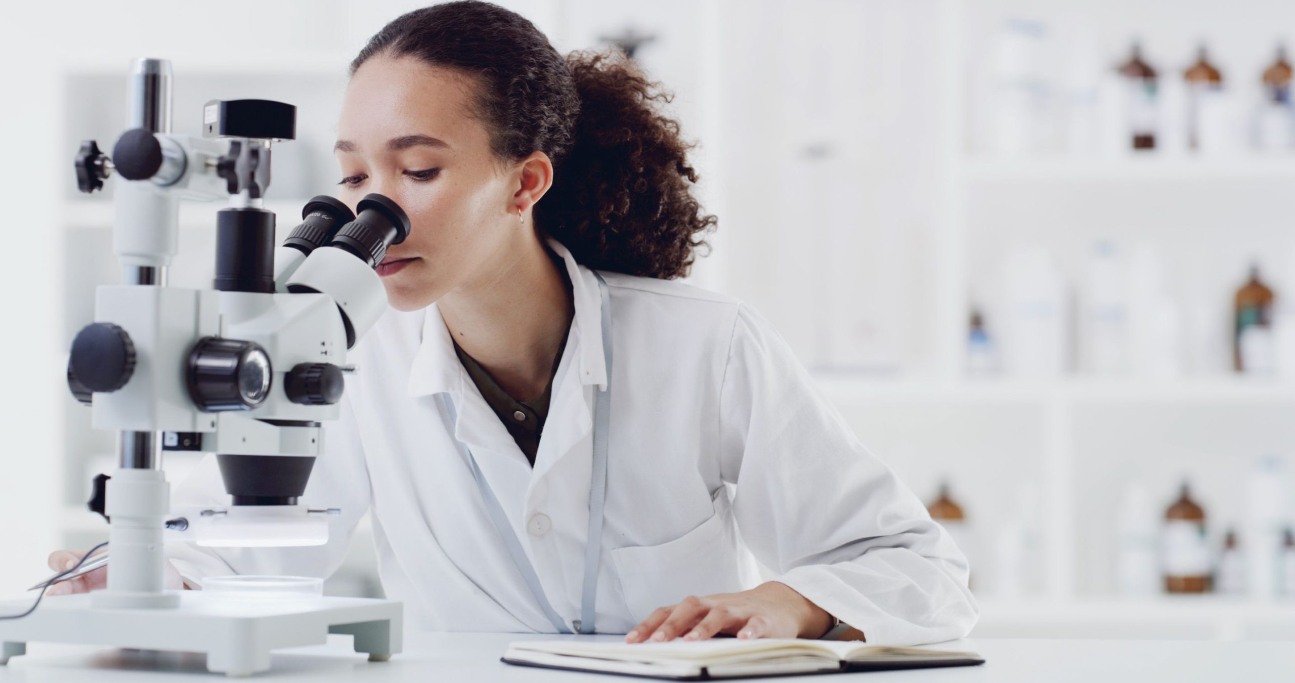 Notes, scientist and woman with microscope in lab for experiment, vaccine development or pharma. Notebook