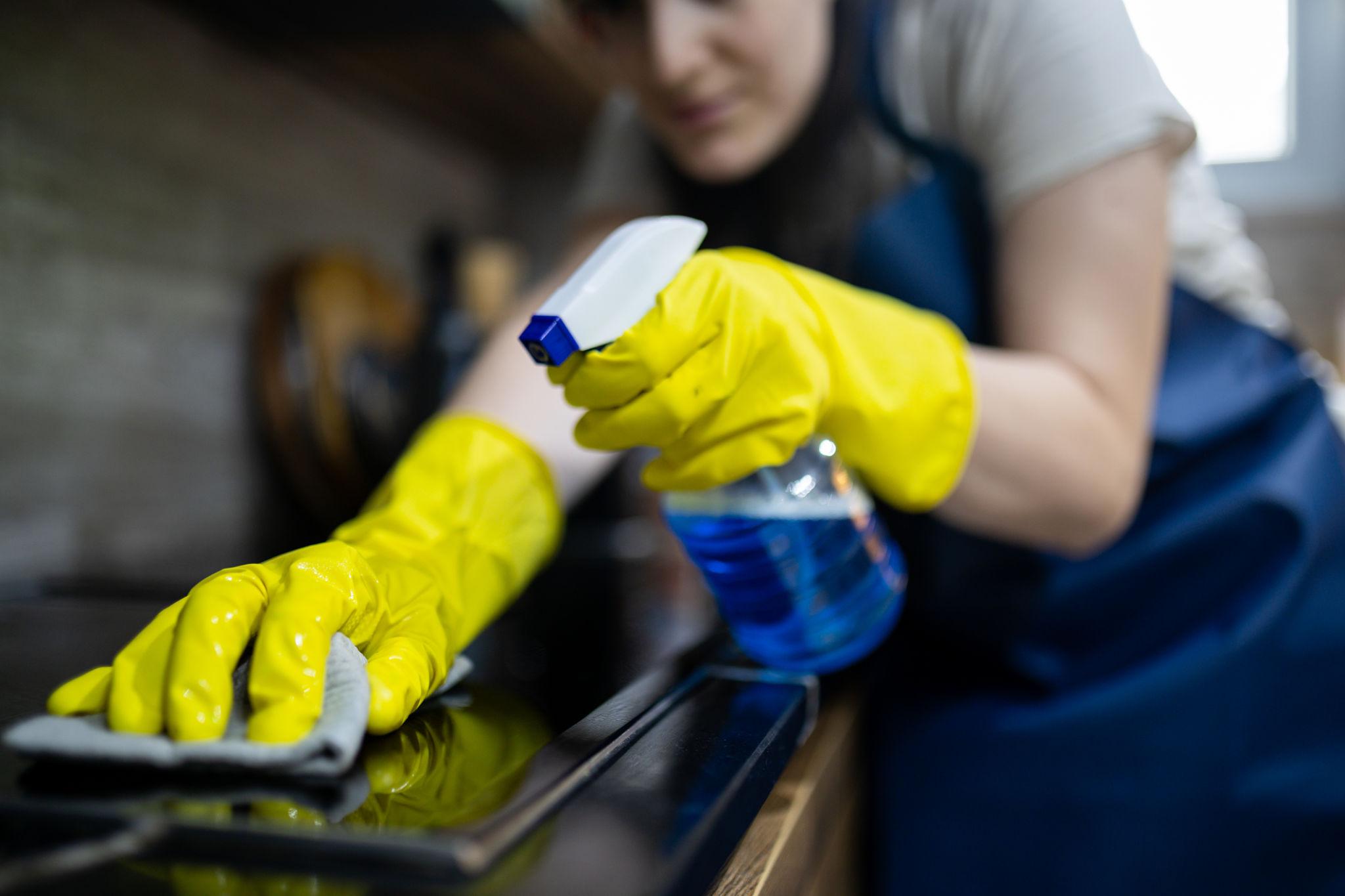 person spraying and wiping a modern kitchen countertop with an all-purpose home care cleaner for everyday surface cleaning