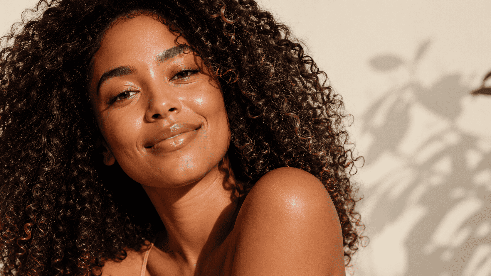 Brazilian woman with healthy natural curly hair, radiant skin, modern beauty editorial photography, warm natural daylight, premium cosmetic industry visual, clean background, shallow depth of field,