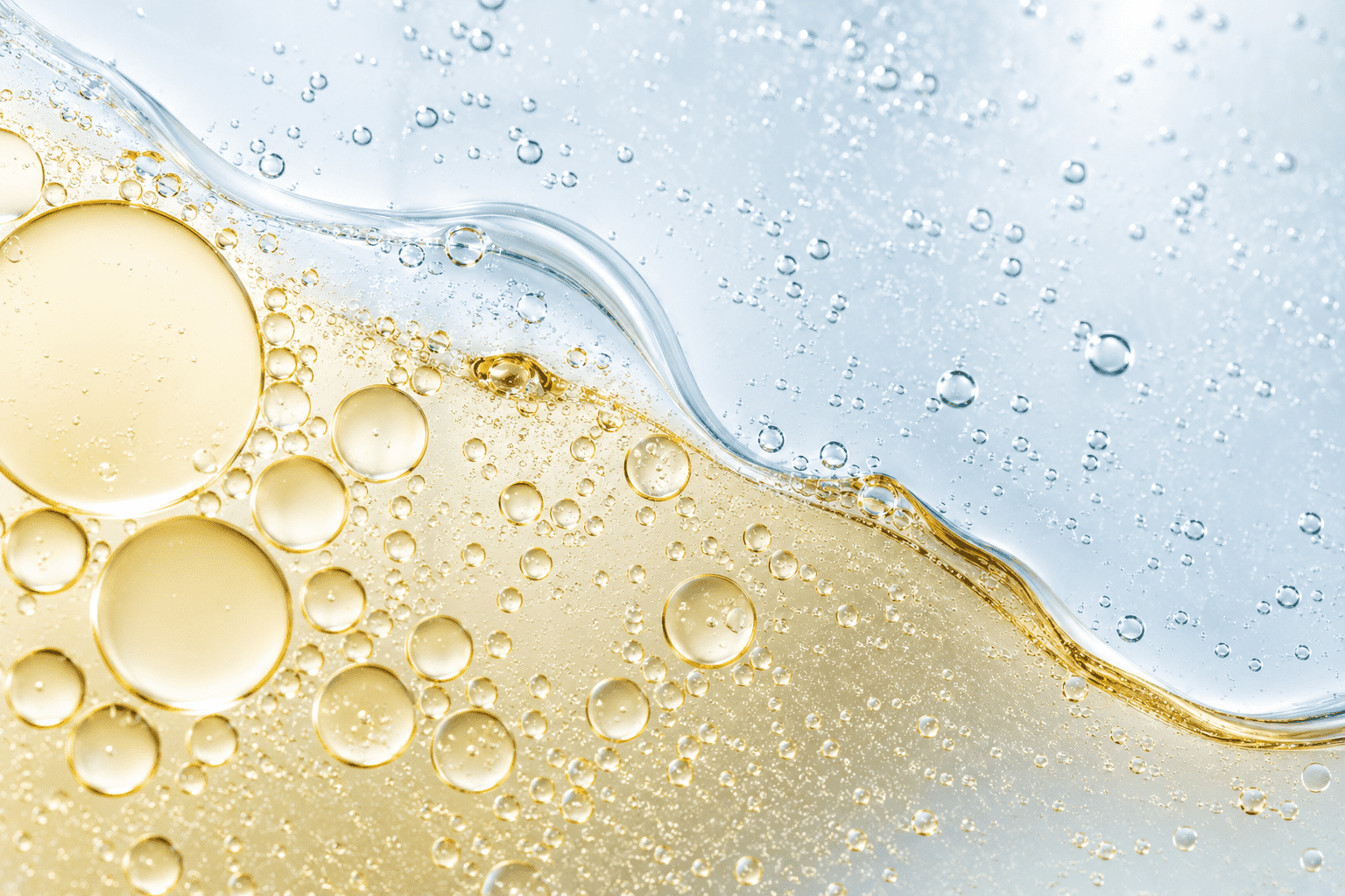 Gotas de óleo dispersas em água formando uma emulsão estável, ilustrando o papel dos tensoativos em formulações cosméticas.