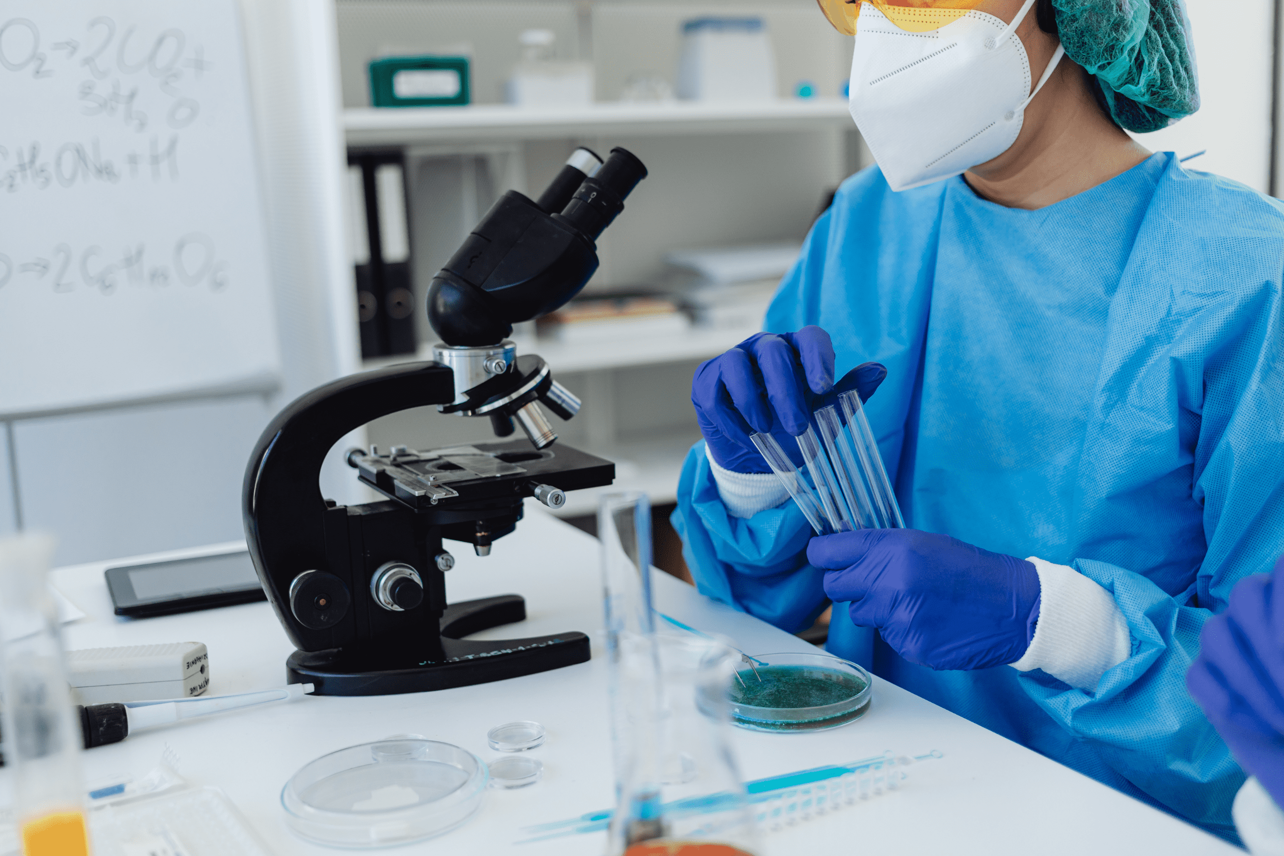 lab person holding pipettes and looking through a microscope