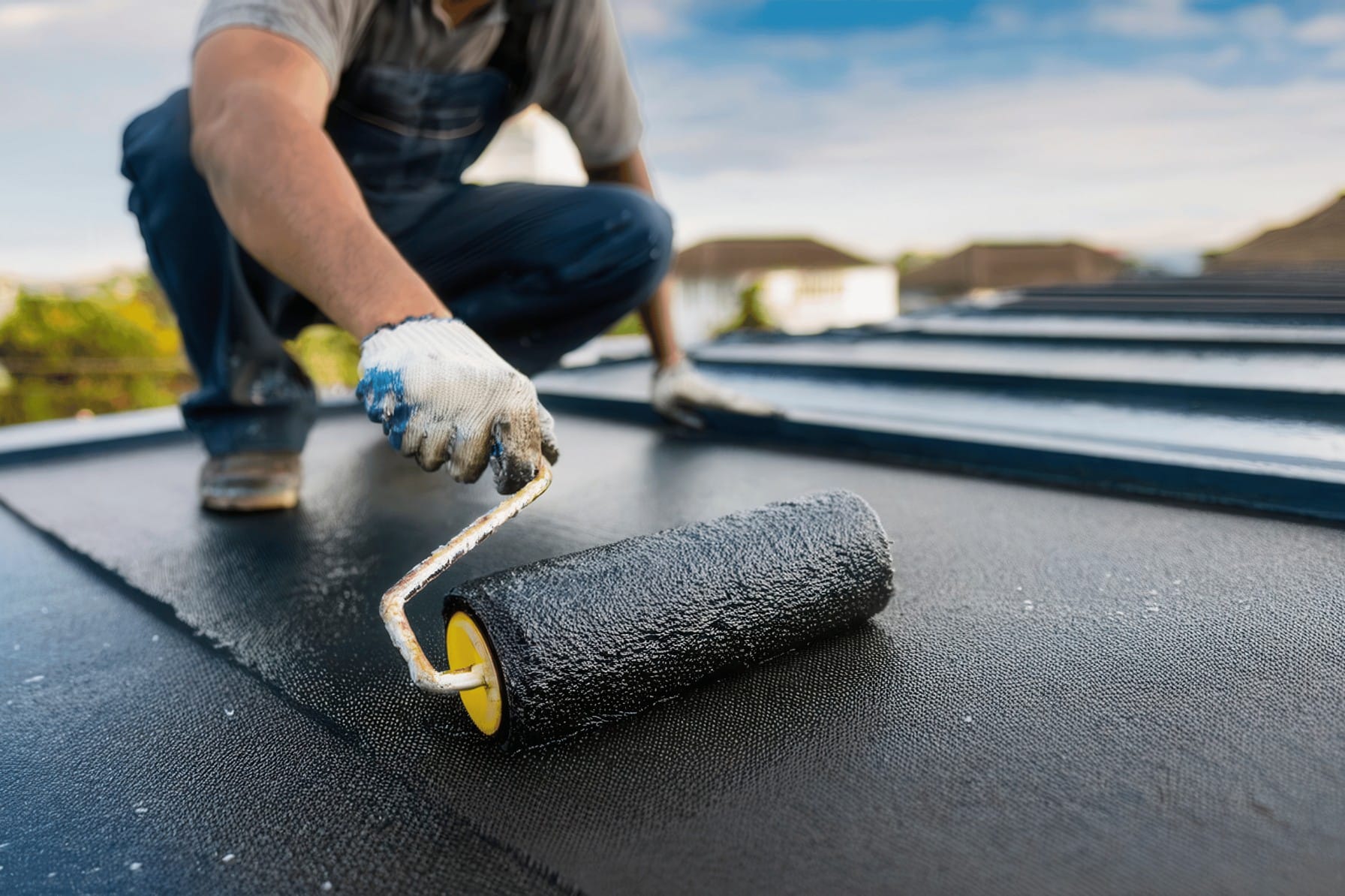 man applying paint onto a roof