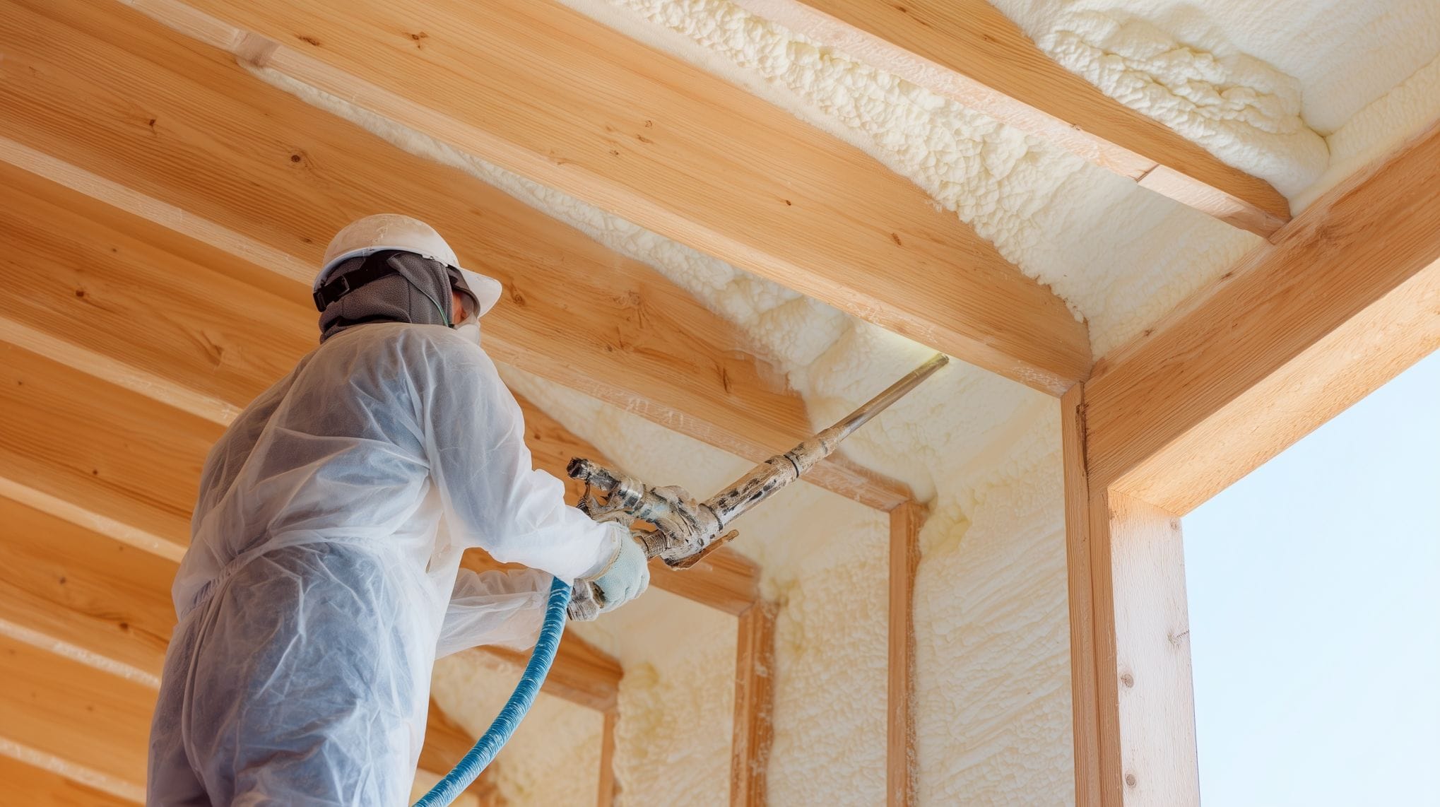 Construction worker using spray gun to apply polyurethane foam insulation.