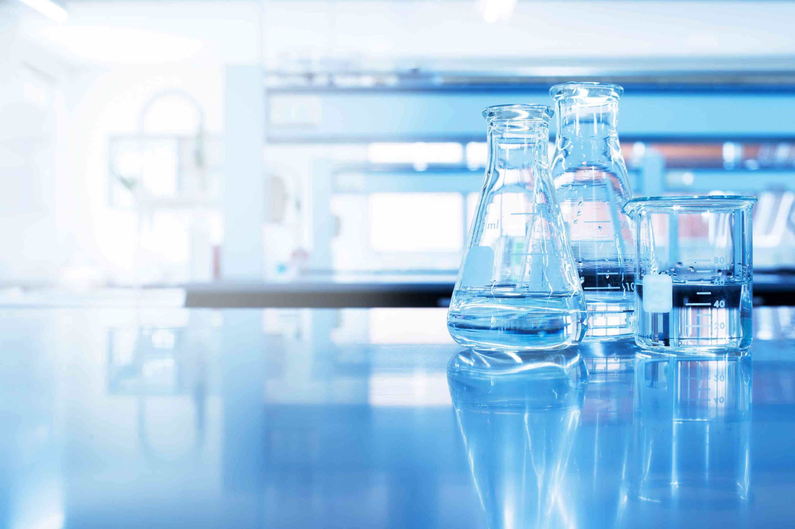 water in beaker and flask glass in chemistry blue science laboratory background.