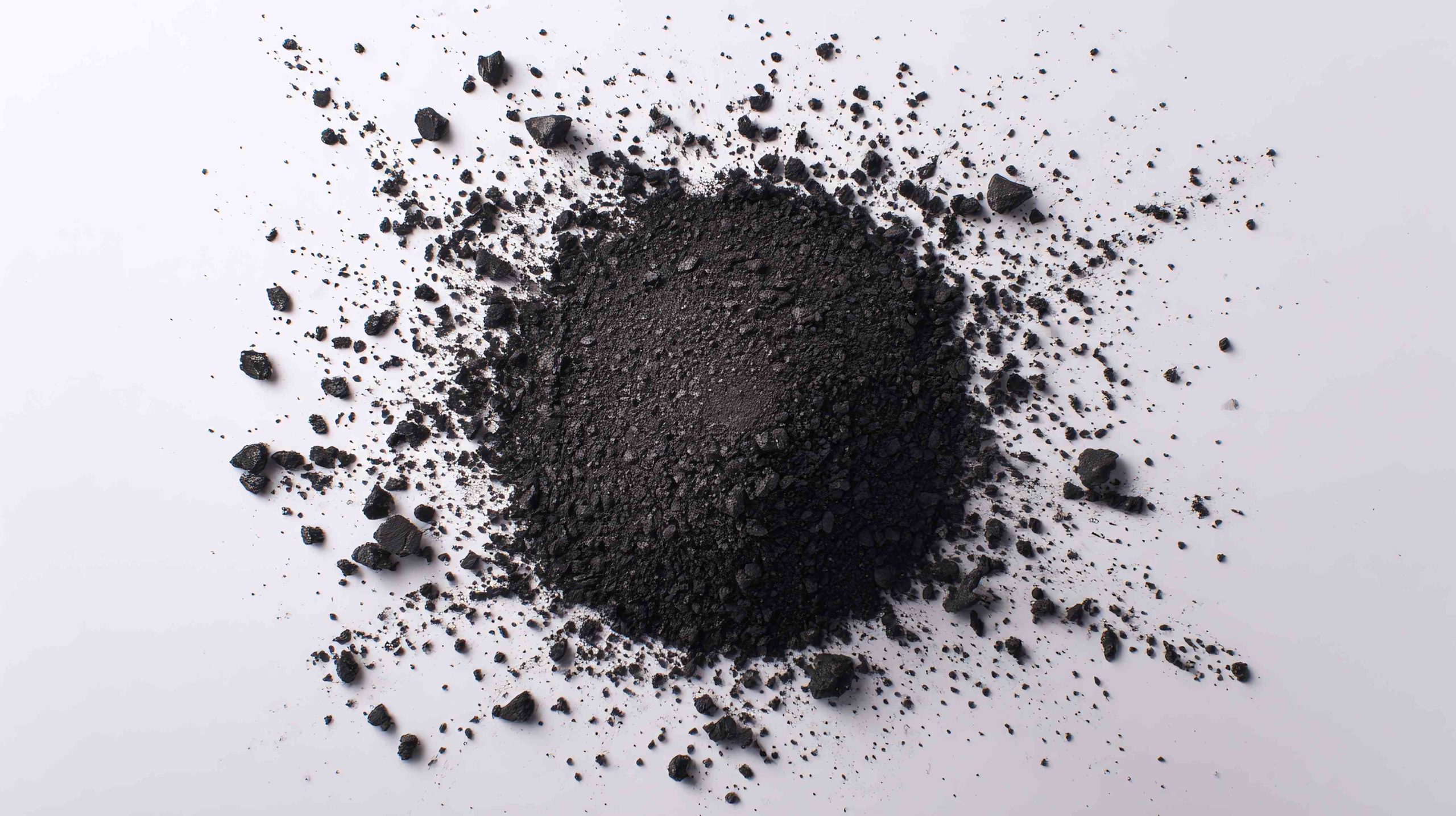 A heap of dark, granular material scattered across a bright surface