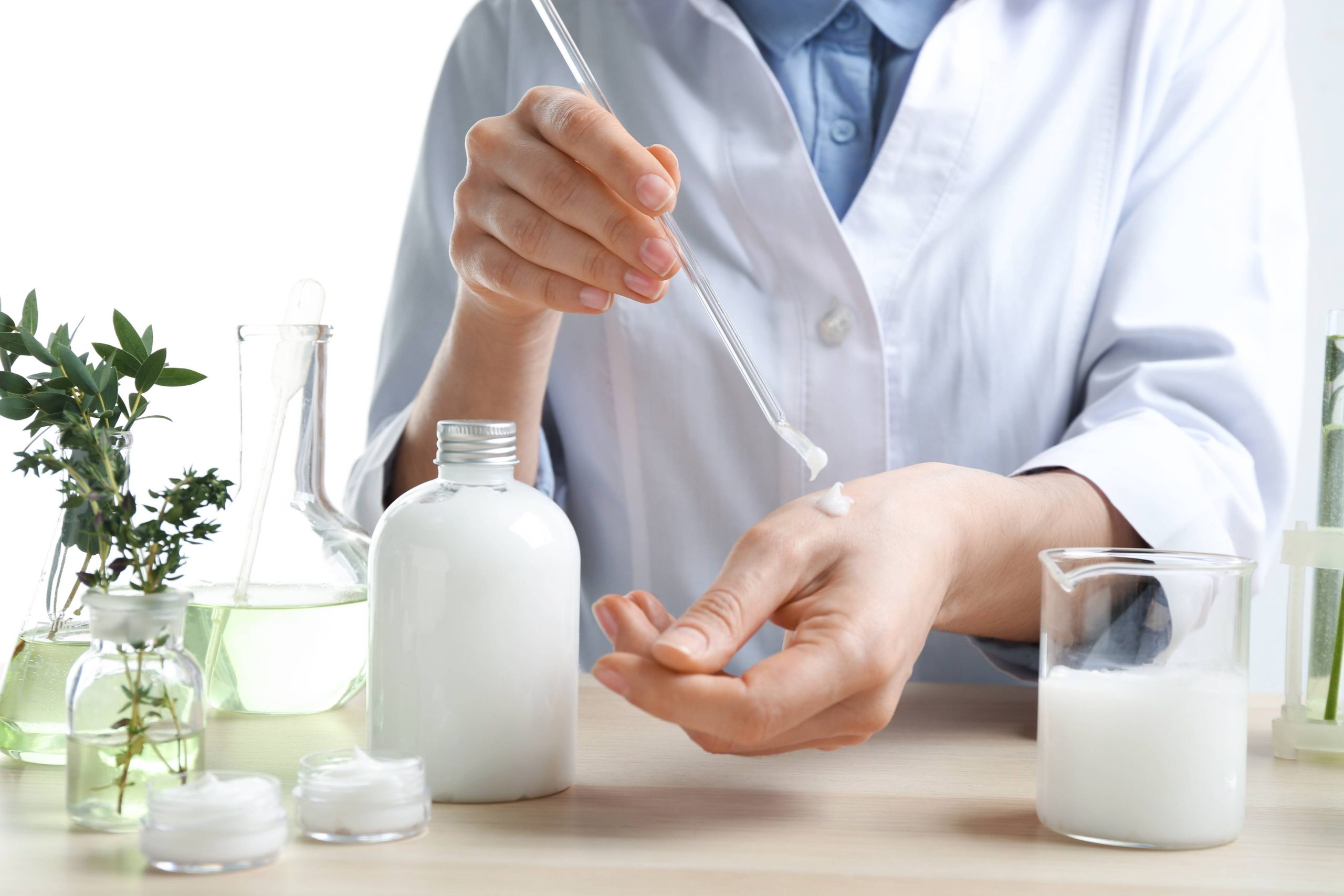 Woman applying natural cream onto hand in cosmetic laboratory, closeup.