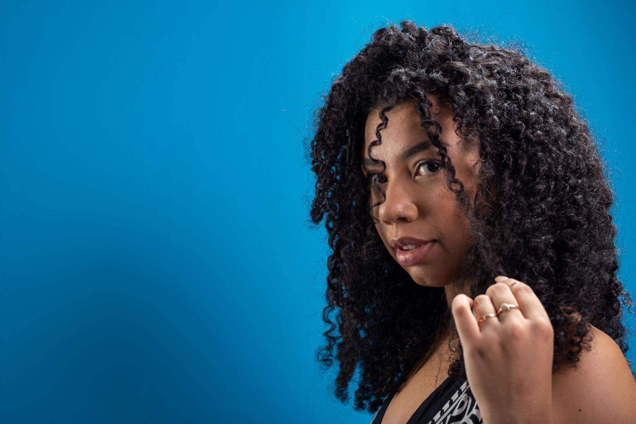 Portrait of beautiful woman touching her curly hair.