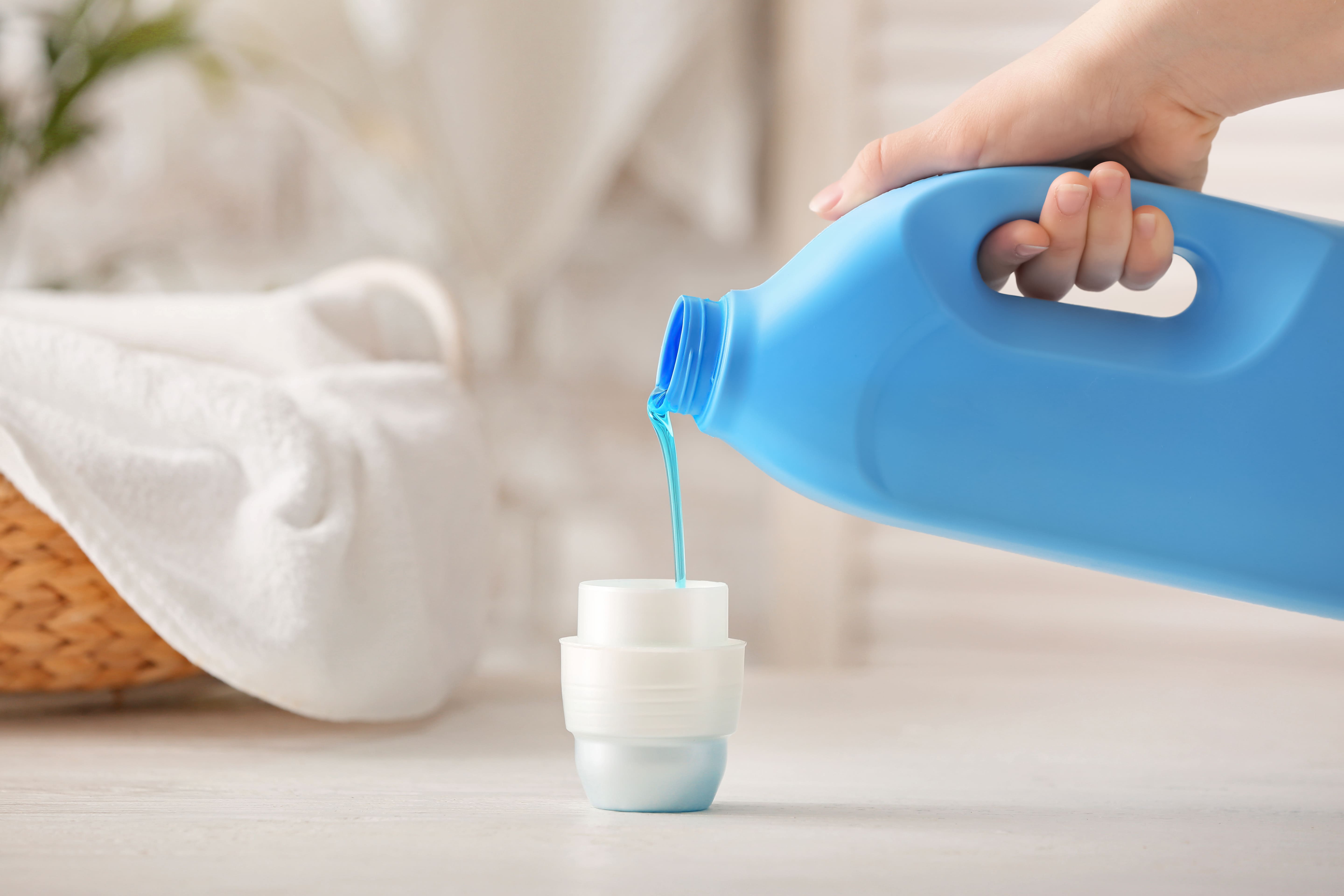 someone pouring laundry detergent in a cup