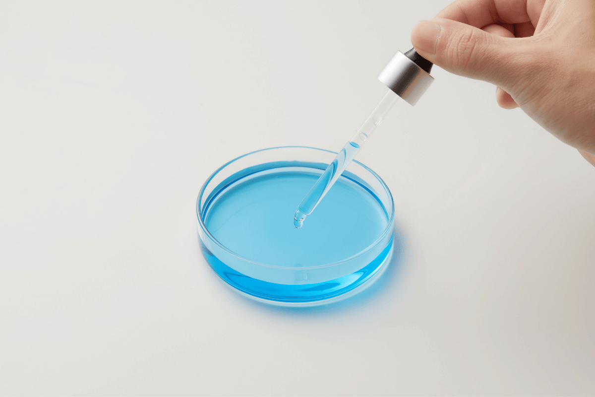 Formulator comparing the spreading of a silicone-free emollient blend with a D5 reference on a glass plate