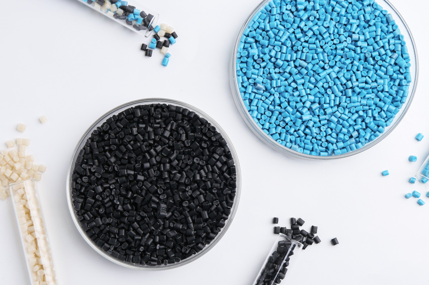 Colorful plastic granules in petri dishes and test tubes on white background, flat lay
