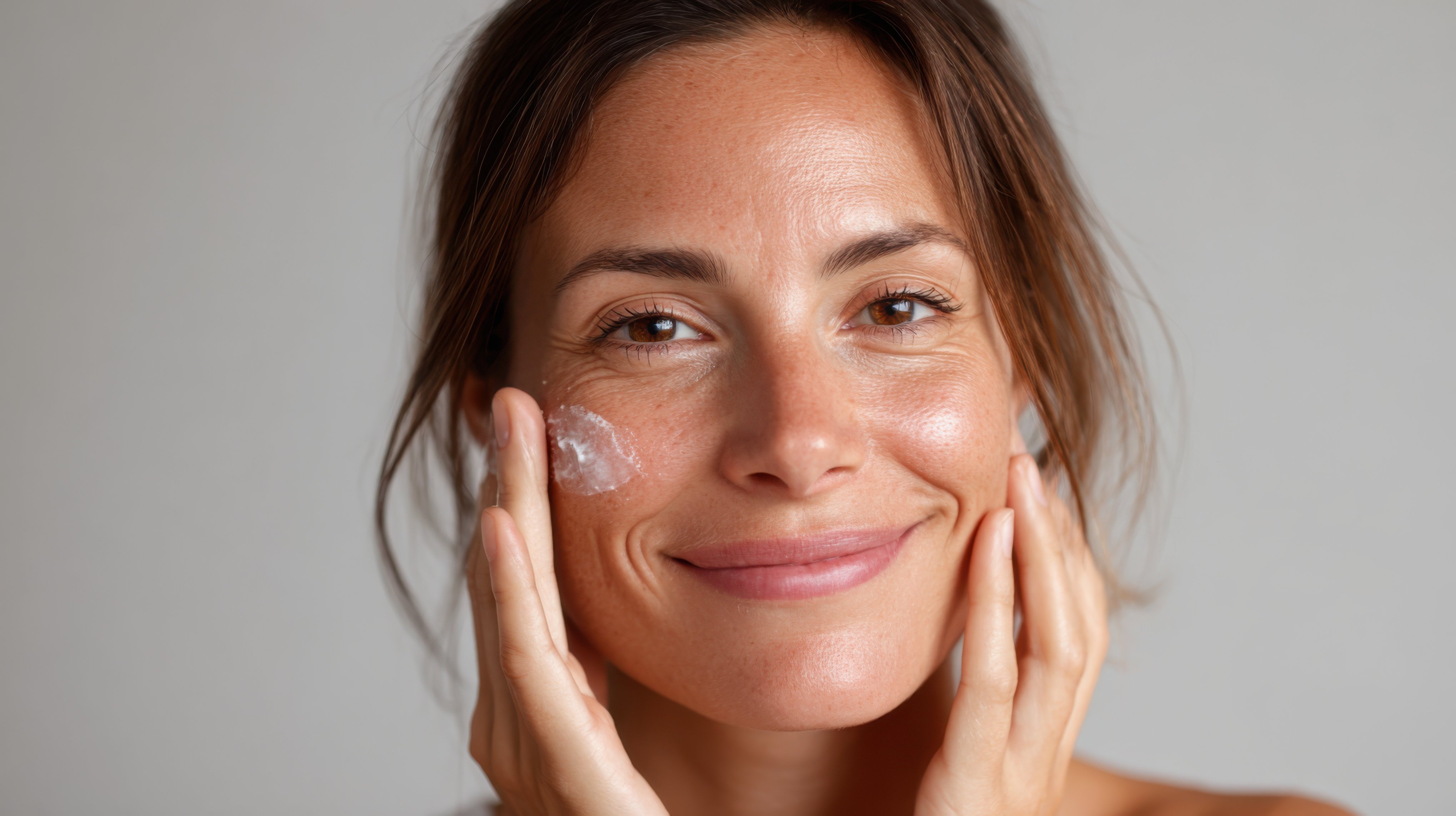 A woman applying cream to her face.