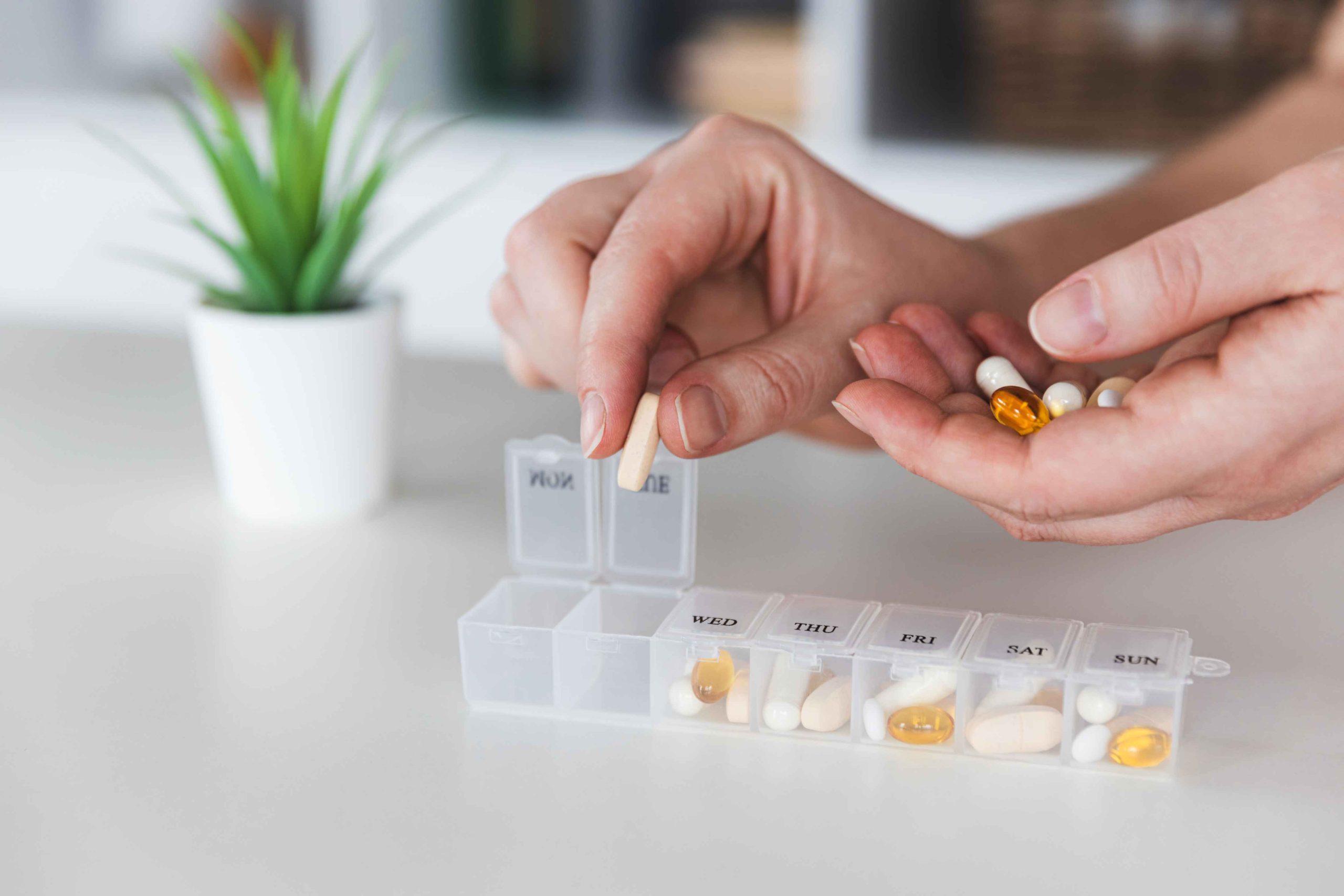 . Closeup of medical pill box with doses of tablets for daily take a medicine with white, yellow drugs and capsules.